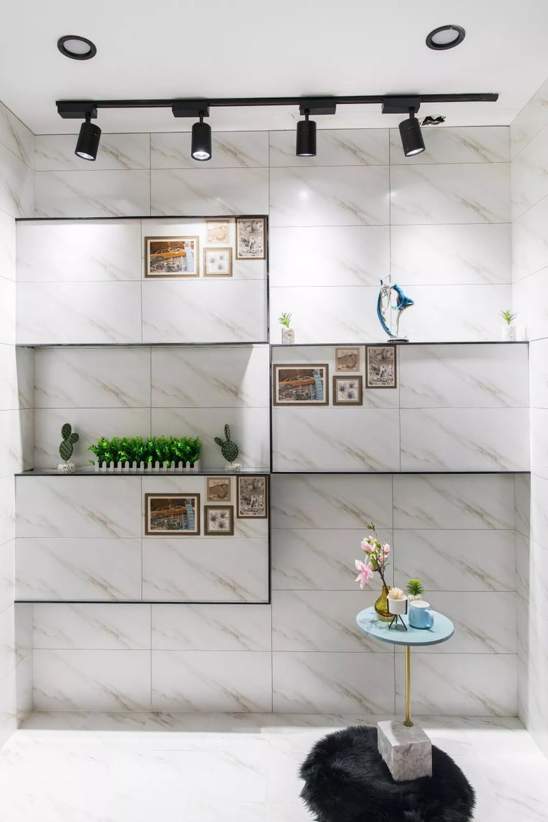White marble-look wall tiles with light brown-gold diagonal veining and recessed shelves