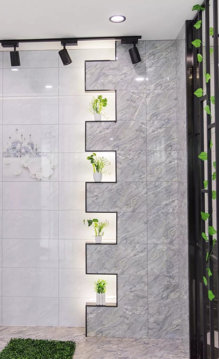 Staggered light-grey and dark-vein marble-look wall with lit plant niches